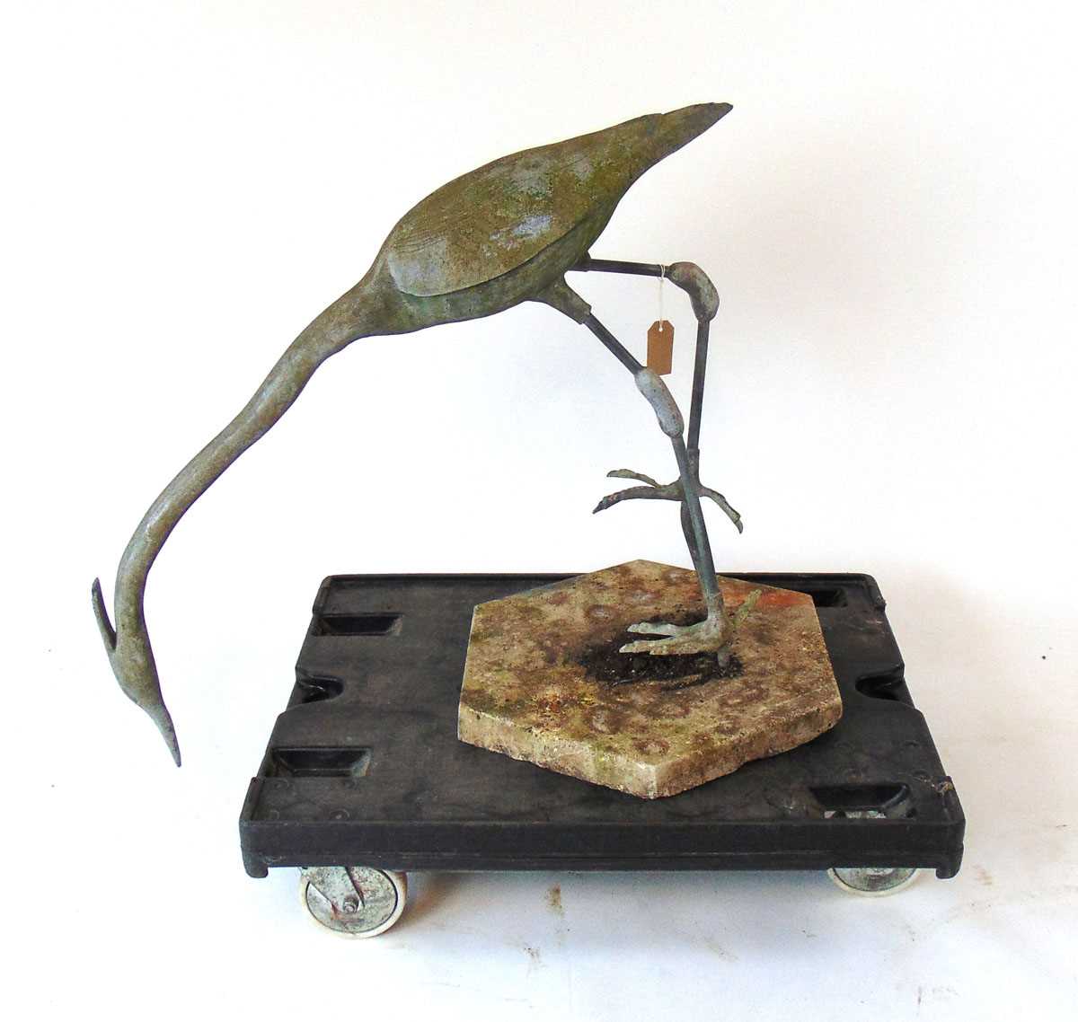 A life size lead Heron garden ornament, modelled facing downwards, on a concrete base, 88cm wide ,