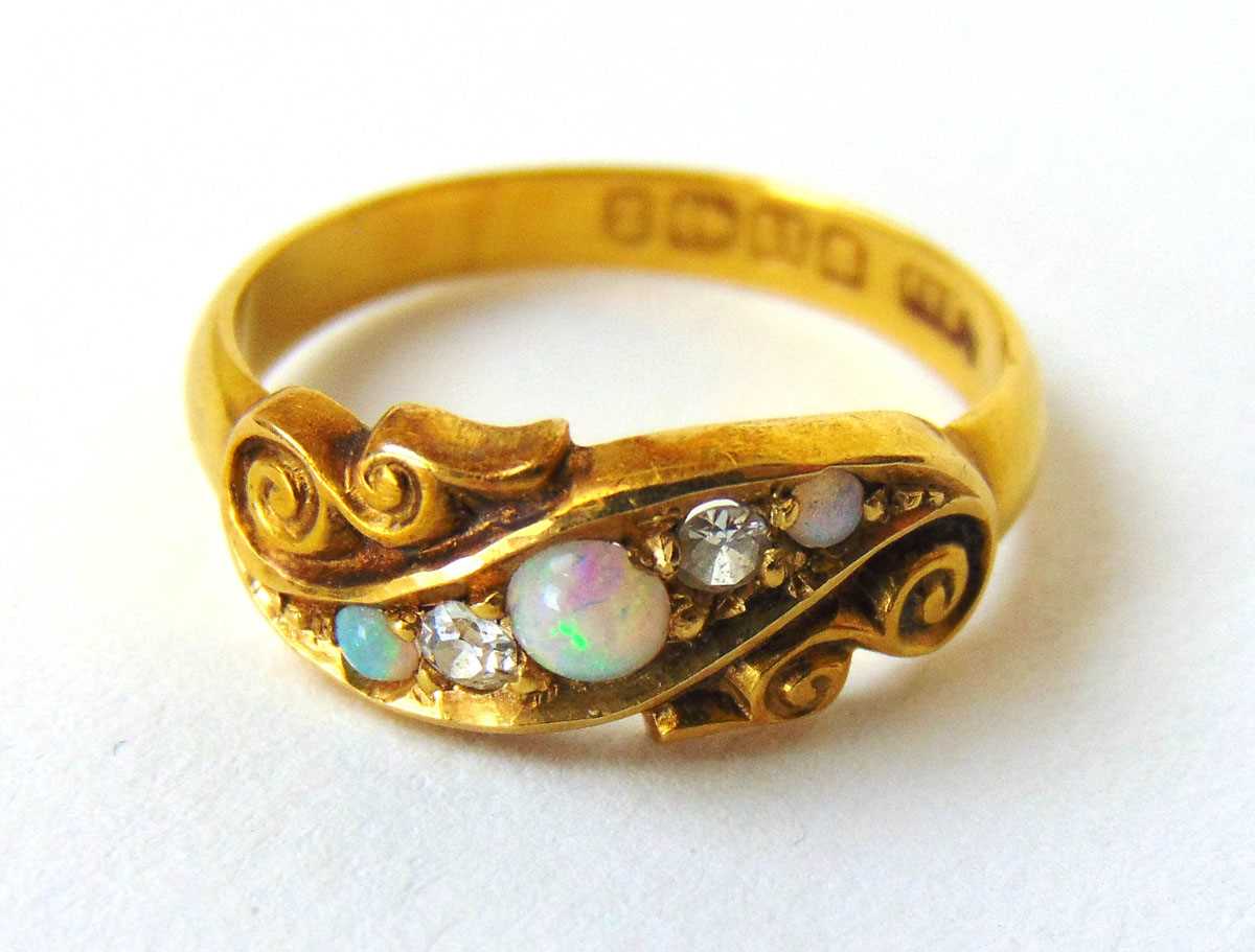 A late Victorian 18ct gold, opal and diamond ring the five stones in a scrollwork setting. Size M.