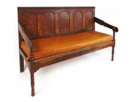 A George III oak settle, with five panel back, the shaped armrests on bobbin turned supports, with