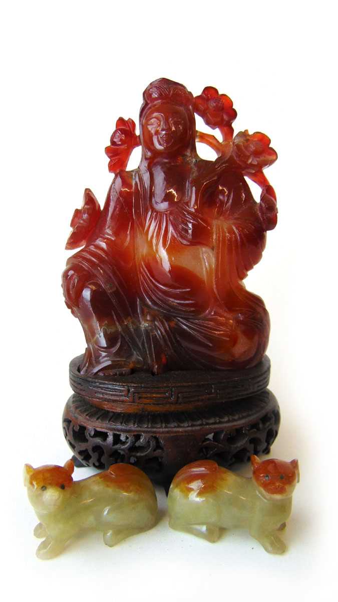 A Chinese carnelain figure of Guan Yin, 20th century, in seated pose holding a branch of