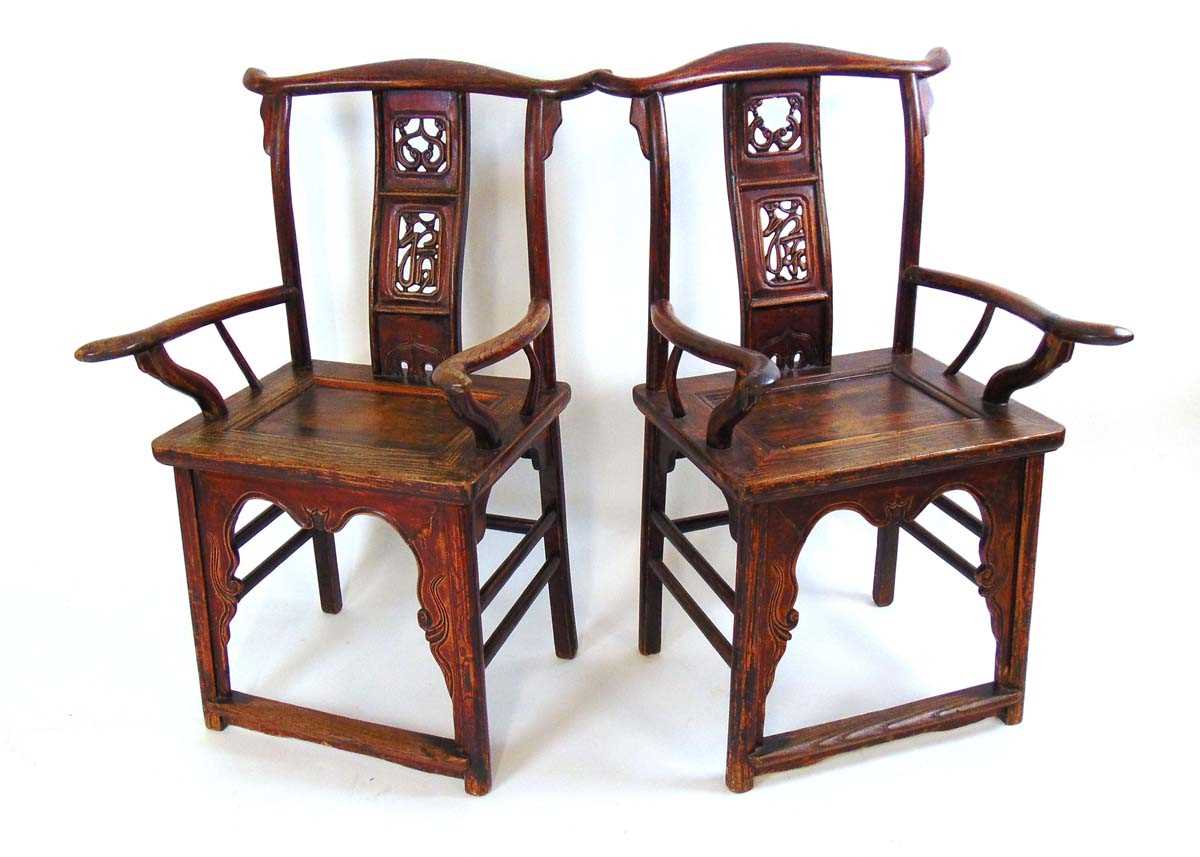 A pair of Chinese elm official hat armchairs, Qing dynasty, the shaped top rail above a pierced ruyi