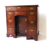 An 18th century mahogany kneehole desk, with applied moulded edge, over an arrangement of one long