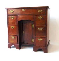 An 18th century mahogany kneehole desk, with applied moulded edge, over an arrangement of one long