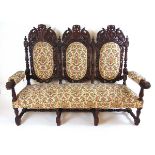 A late 19th century Flemish carved oak settee, the dark stained oak show frame carved with