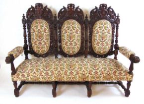 A late 19th century Flemish carved oak settee, the dark stained oak show frame carved with