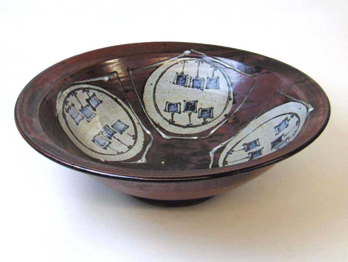 A large studio pottery bowl, the interior decorated with a four pentagons framing roundels each with