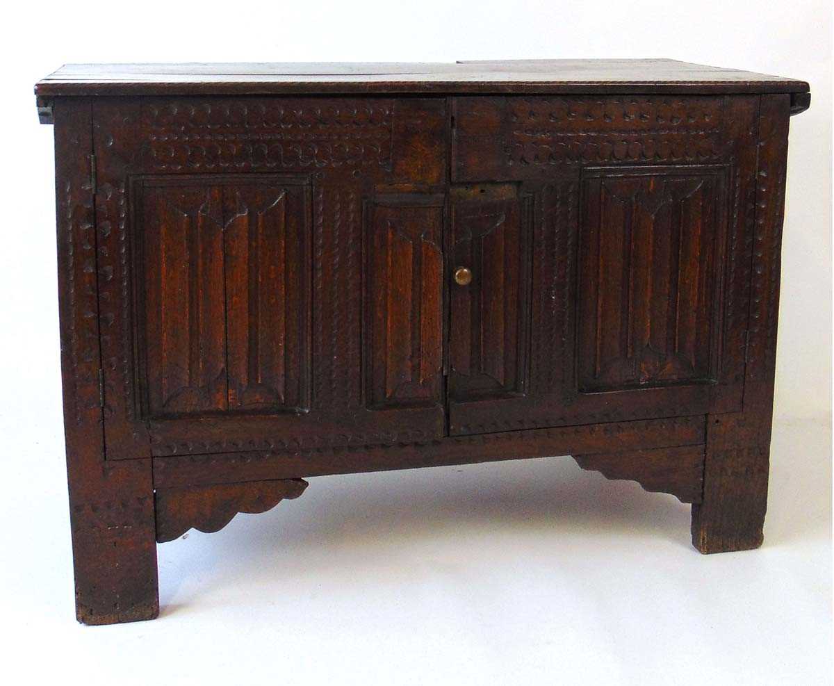 An early 18th century oak blanket box, later converted to a cupboard, with carved linen fold panels,