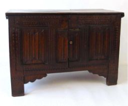 An early 18th century oak blanket box, later converted to a cupboard, with carved linen fold panels,