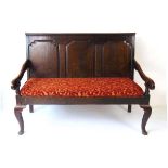 A George III oak settle, with three shaped panel back, the solid seat with squab cushion, on