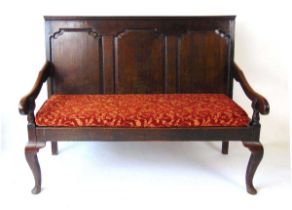 A George III oak settle, with three shaped panel back, the solid seat with squab cushion, on
