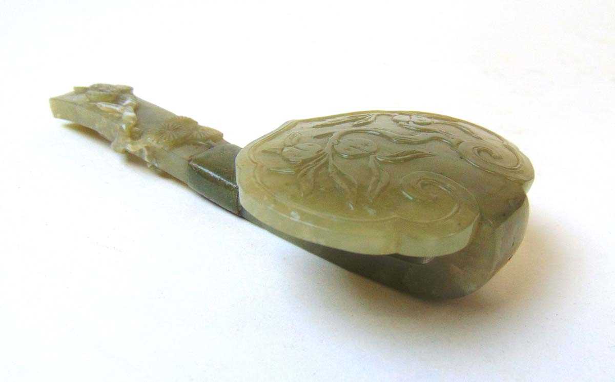 A Chinese carved jade section of a ruyi sceptre, Qing, the head carved with peaches on a leafy
