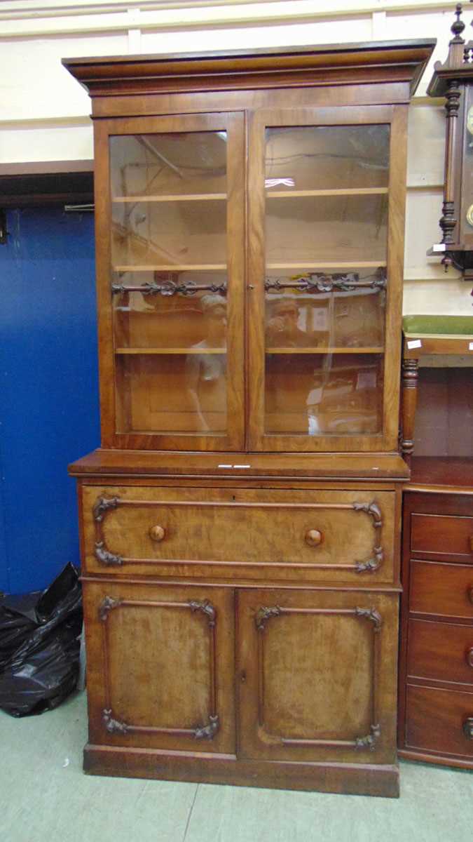 An early 19th century mahogany bookcase on cupboard base, with moulded pediment above glazed doors