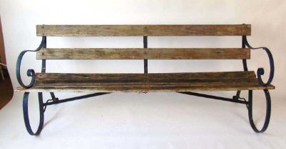 A late Victorian green painted wrought iron and wooden slatted garden bench on scrolled supports,