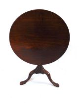 A George III mahogany tilt top occasional table, having a circular one piece top on turned support
