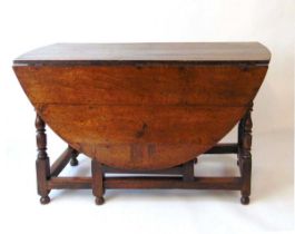 A Geo III oak drop leaf dining table, with elliptical leaves and a single frieze drawer, on turned