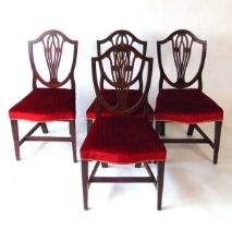 A set of four mahogany shield back dining chairs, early 19th century, with stuff over seats, on