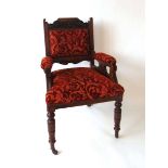 A Victorian upholstered armchair with carved oak show frame, the top rail with carved foliate