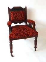 A Victorian upholstered armchair with carved oak show frame, the top rail with carved foliate