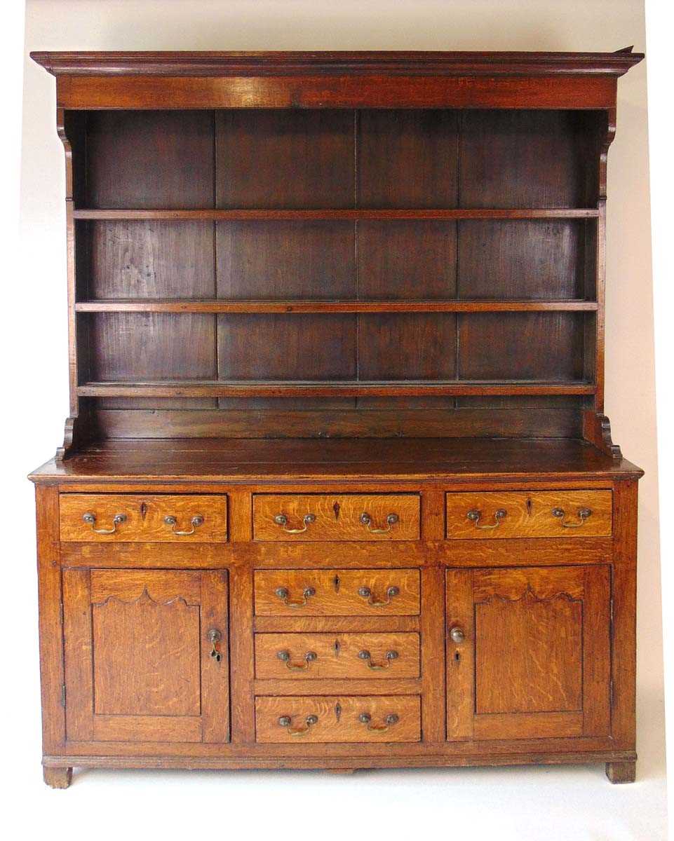A George III oak Welsh dresser, with cavetto moulded pediment above the boarded back with three
