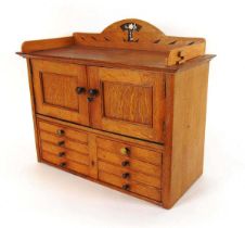 An early 20th century table top oak cabinet, with blind gallery above two cupboard doors and eight