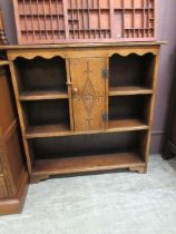 A mid-20th century oak cabinet having open shelving flanking carved panel door