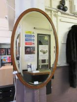 A mahogany and banded oval framed bevel glass wall mirror