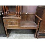 A mid 20th century oak hall table with seat and cupboard door with linenfold design