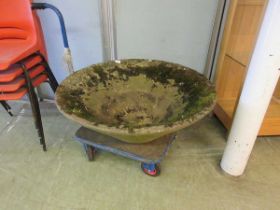 A large circular weathered concrete planter