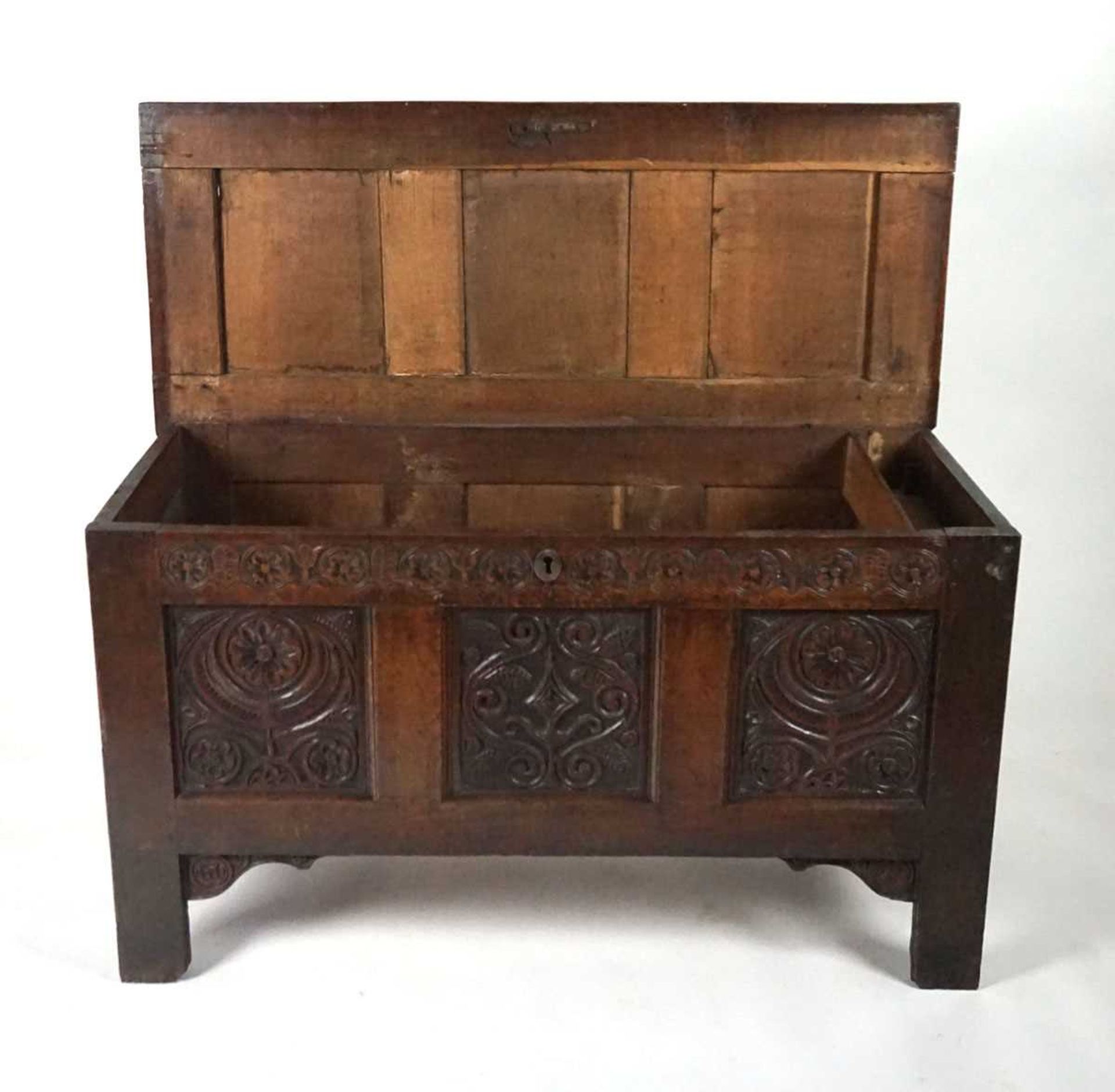 An 18th century oak coffer, the top with three recessed panels, above a carved frieze of roses and - Image 4 of 9