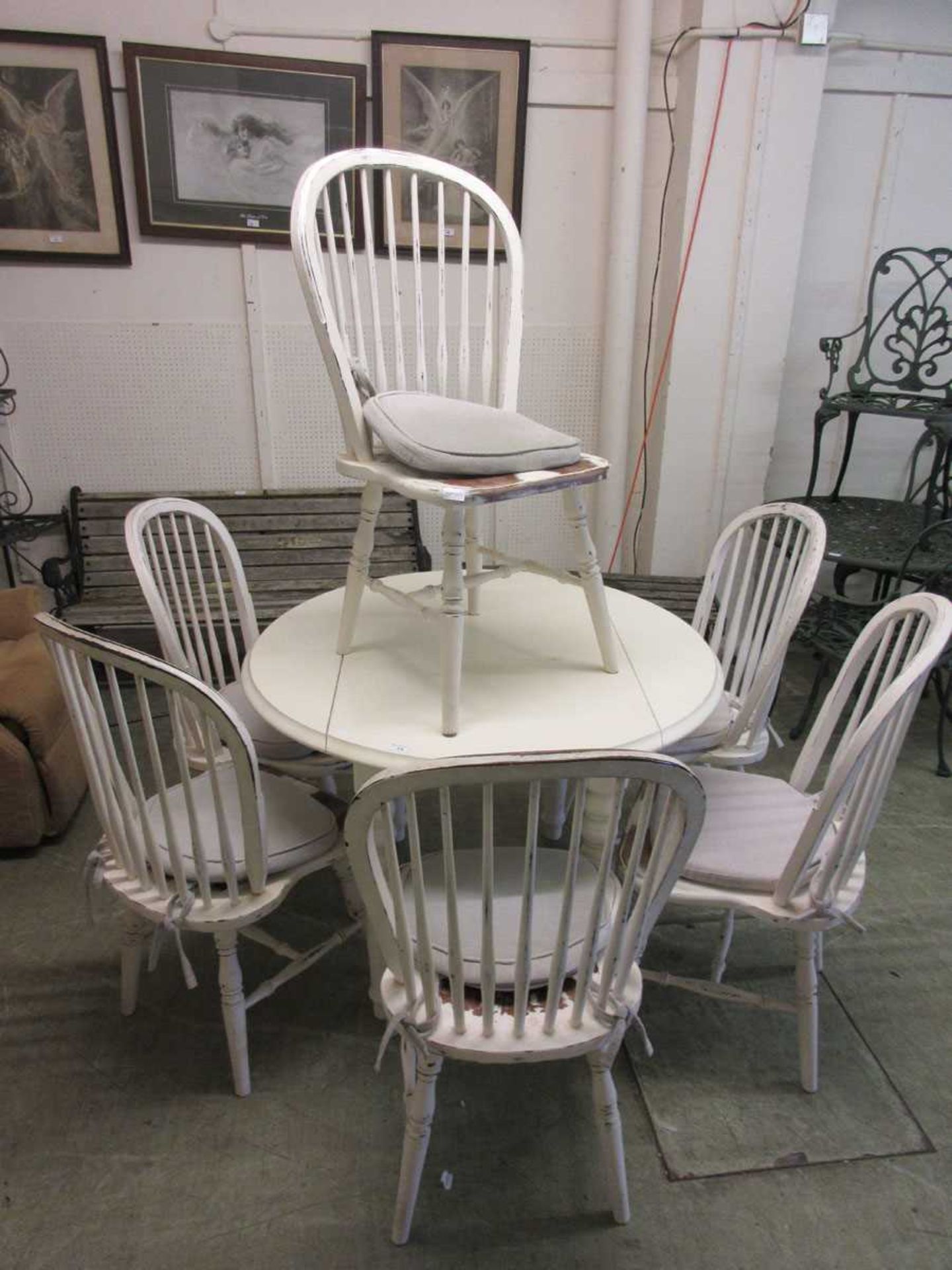A white circular dropleaf kitchen table together with a set of six painted stick back chairs