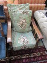 A 1950s oak framed easy chair with green floral upholstery