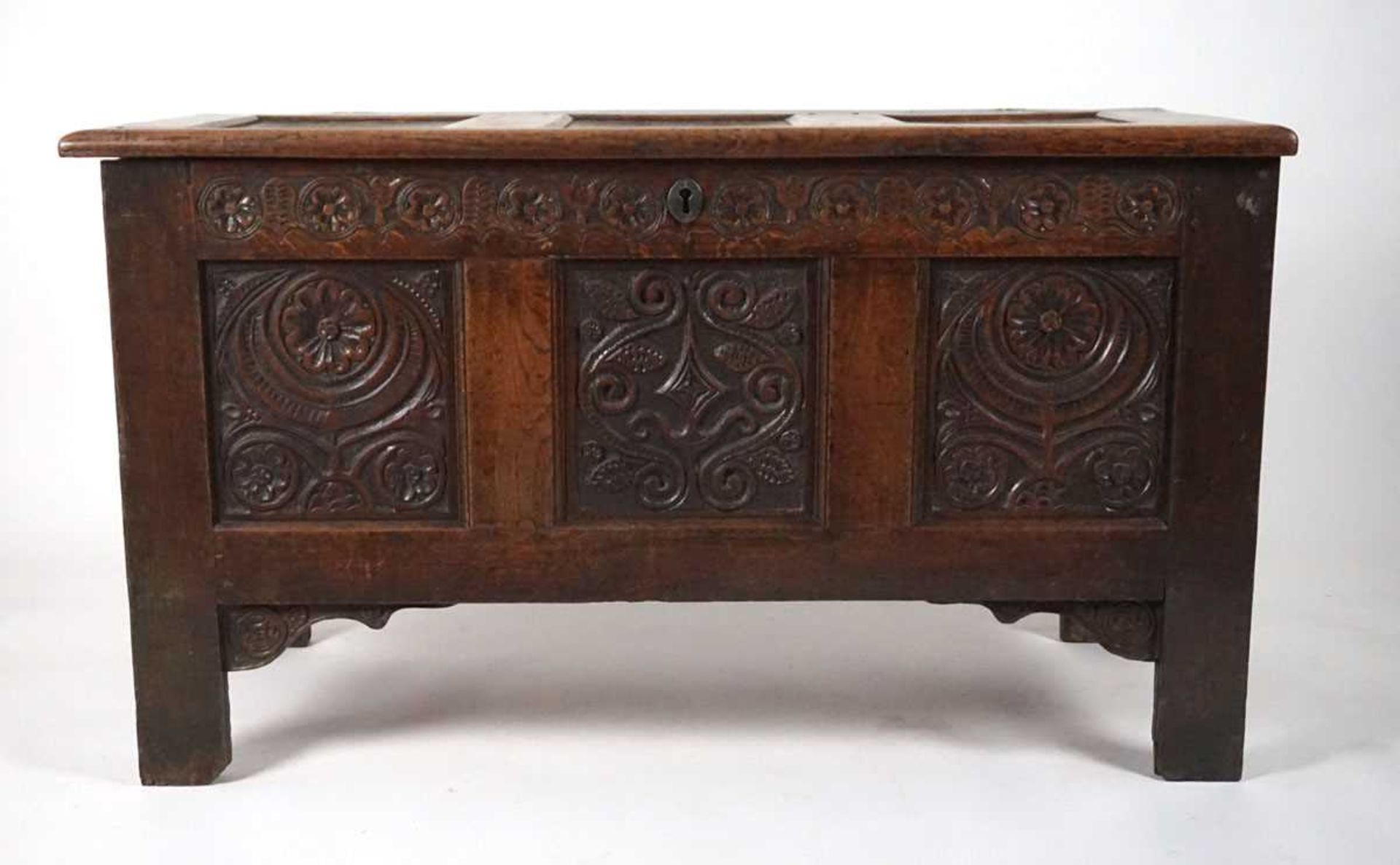 An 18th century oak coffer, the top with three recessed panels, above a carved frieze of roses and - Image 2 of 9