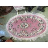 A pink floral patterned Chinese oval rug