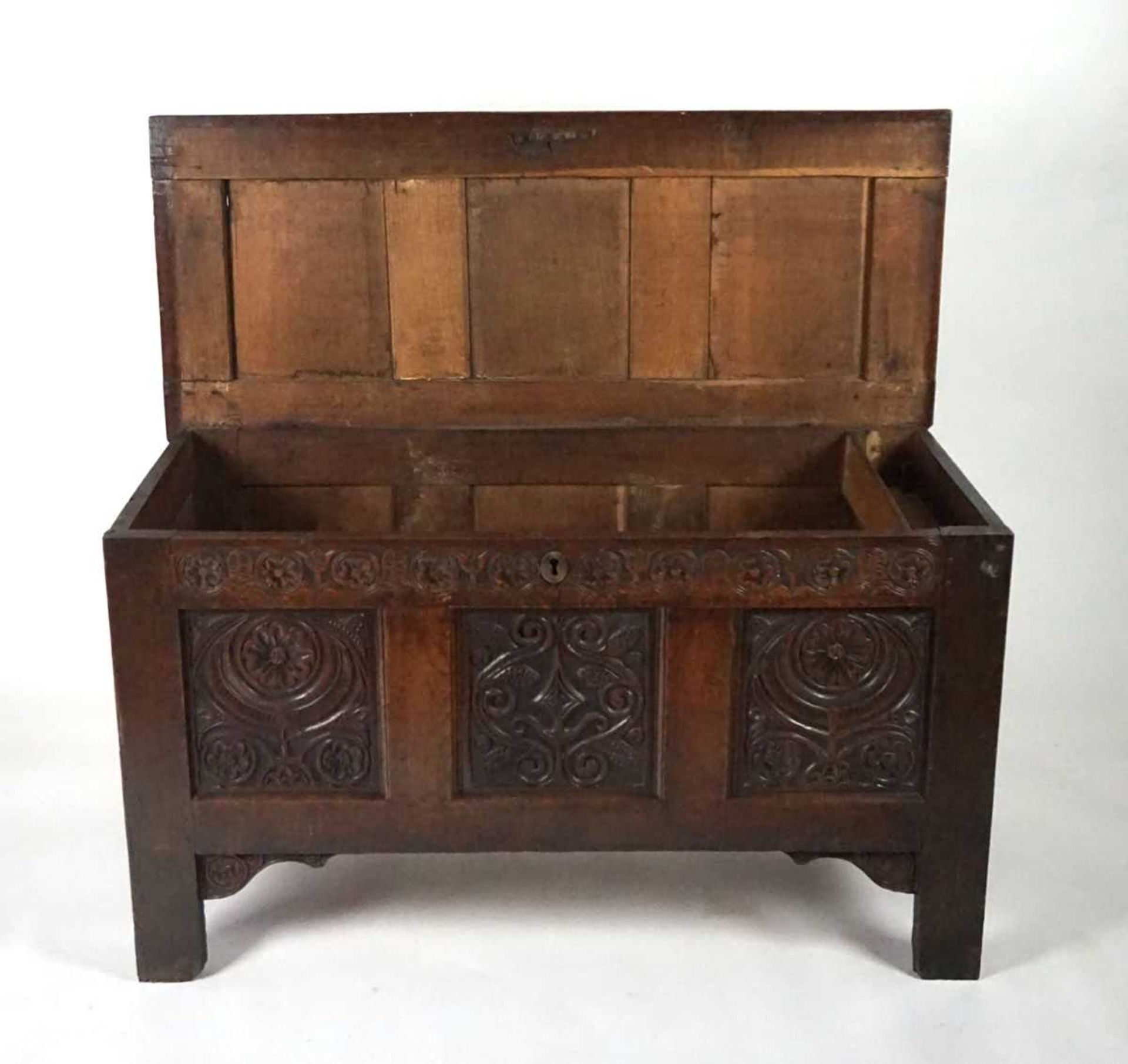 An 18th century oak coffer, the top with three recessed panels, above a carved frieze of roses and - Image 5 of 9