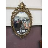 An oval beveled and gilt framed wall mirror
