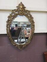 An oval beveled and gilt framed wall mirror