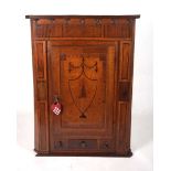 A provincial 19th century oak wall mounted corner cupboard, the door with inlaid ebony shield