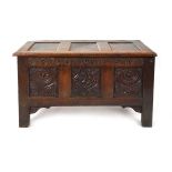 An 18th century oak coffer, the top with three recessed panels, above a carved frieze of roses and