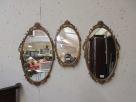 A set of three oval gilt framed mirrors