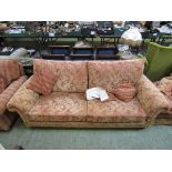 A large three seater sofa along with a pair of similar chairs upholstered in salmon and beige floral