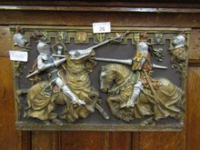 A cast metal wall plaque depicting jousting knights
