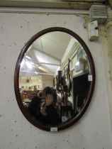 An Edwardian Sheraton revival mahogany inlaid oval bevel glass wall mirror