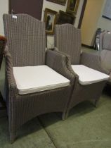 A pair of wicker garden chairs with white cushions