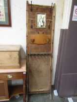 A bamboo and wicker hall stand having a central mirror and hooks