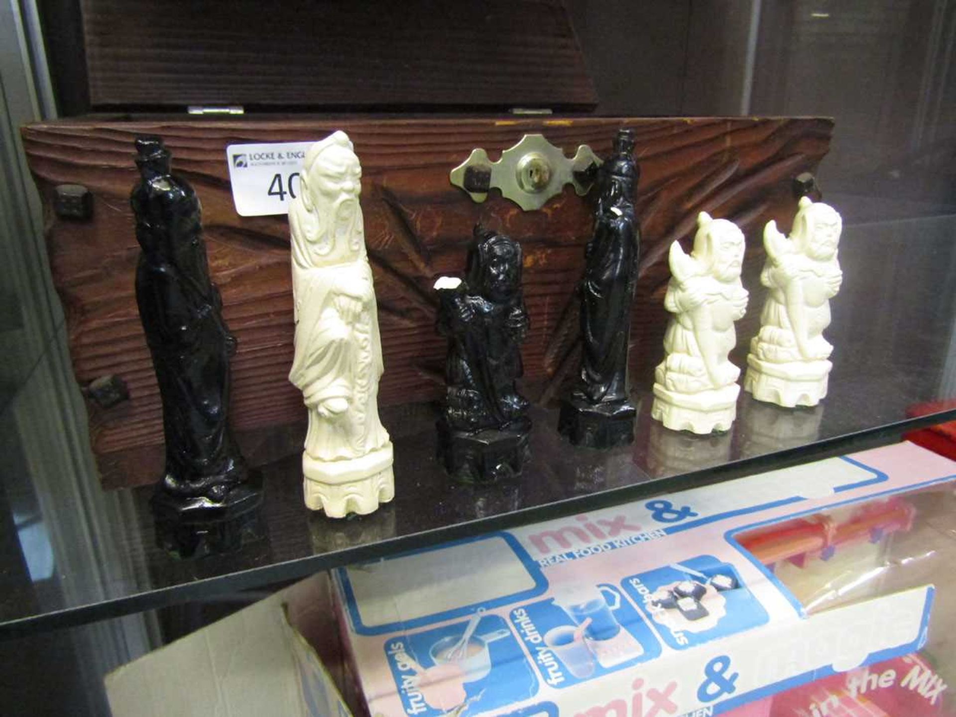 A carved oak hinge top box containing a selection of painted wooden chess pieces - Image 2 of 2