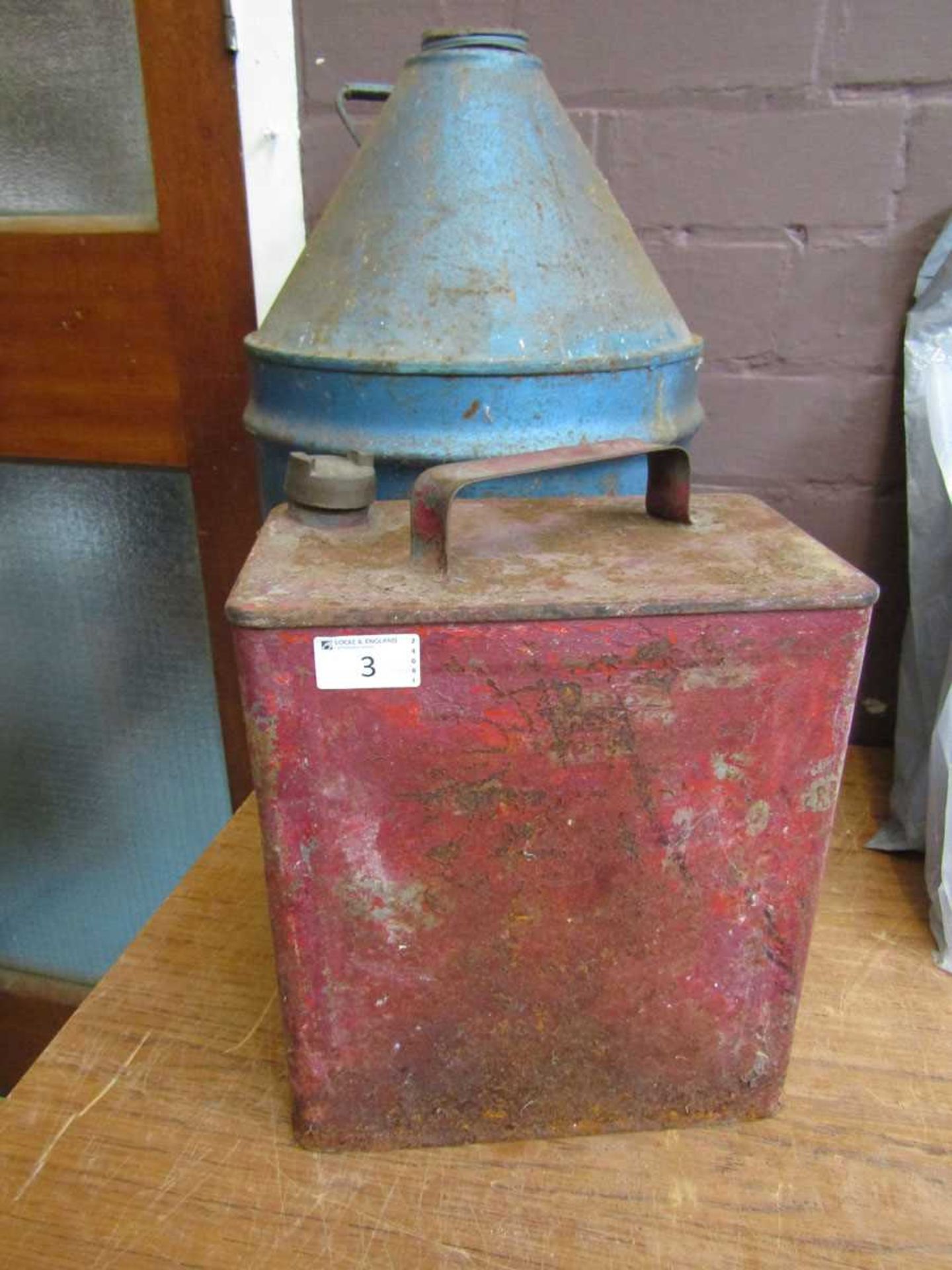 An early 20th century red metal petrol can along with a blue painted paraffin can