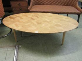 A modern oval parquet effect topped coffee table on cylindrical legs