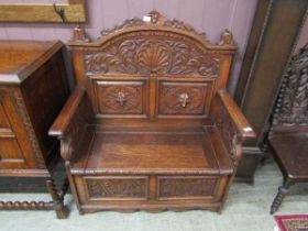 A late 19th century carved oak box settle, profusely carved with central shell, foliate scrolls