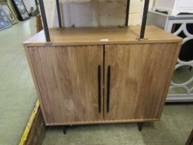 A modern veneered two door cabinet on cylindrical legs, the cupboard doors enclosing open storage