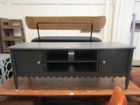 A modern grey painted TV unit, the top over open storage flanked by two cupboard doors